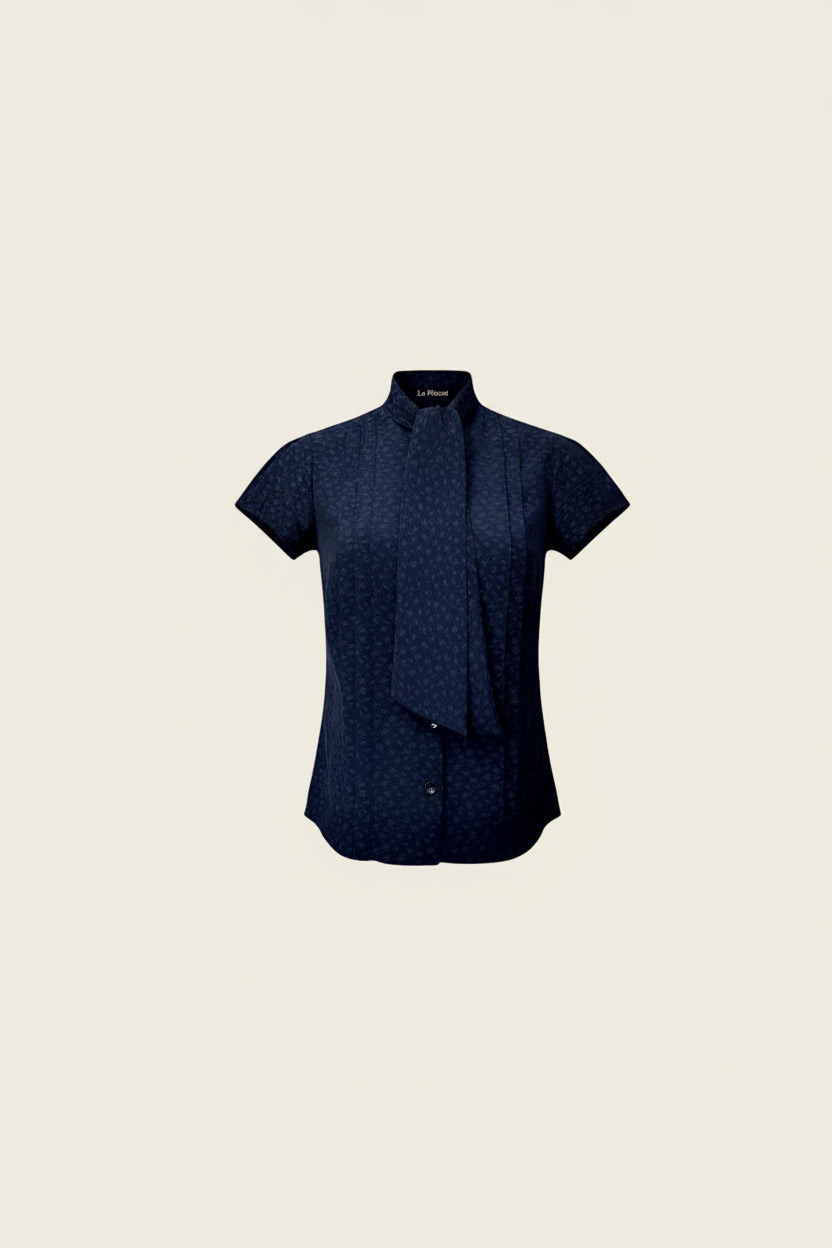 Navy short-sleeve button-front blouse with high neck and tonal allover motif, laid flat.